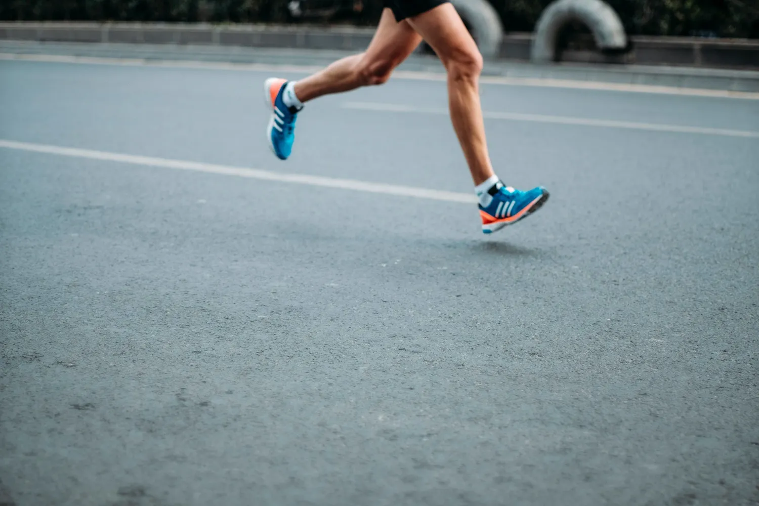 Runner mid-stride on an open road, both feet off the ground